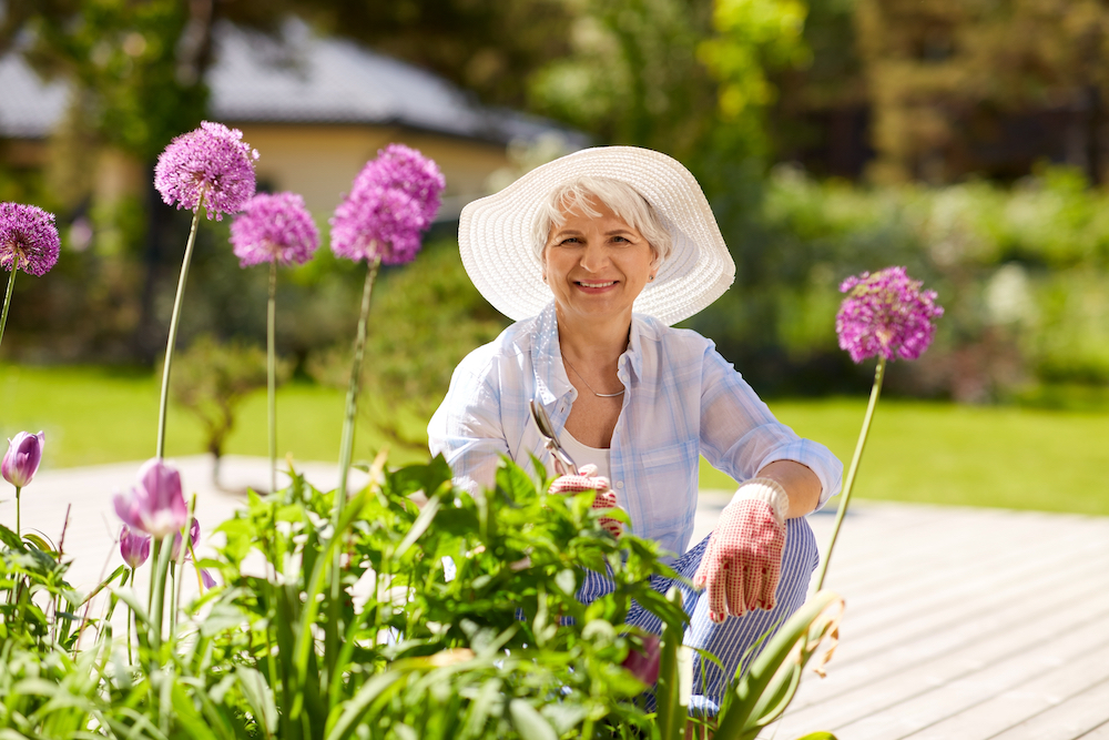 A smiling senior woman working in her garden and tending to her flowers