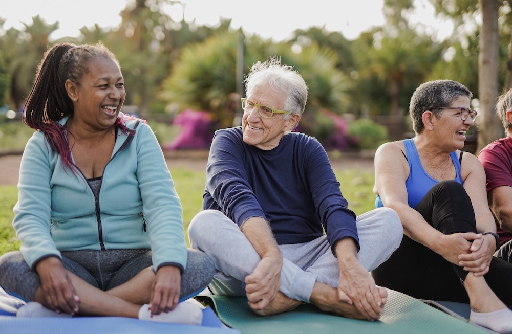 A group of senior living residents participate in an outdoor yoga class