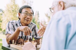 Two senior friends play chess together at the memory care services in Norwalk