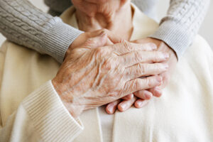 A close up of senior hands offering comfort at the memory care services in Norwalk