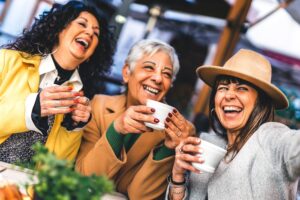 Three senior women having coffee and laughing together