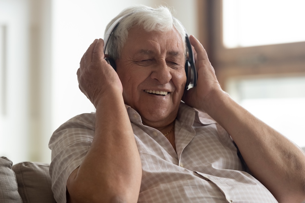 A happy senior man listening to music on wireless headphones