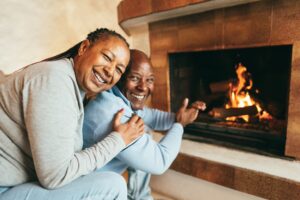 A senior couple warms up by a fireplace