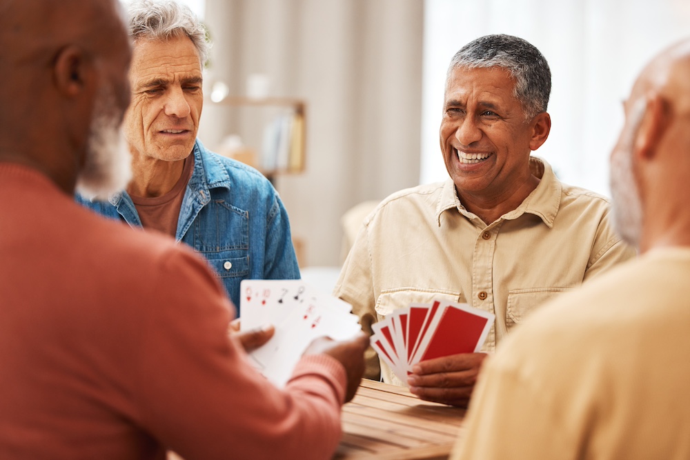 A group of senior men playing cards while enjoying a Norwalk short-term stay