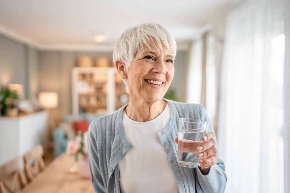 A smiling senior woman holding a glass of water